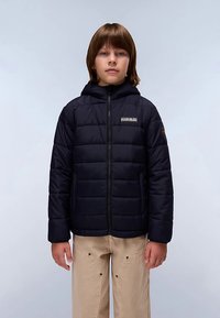 Chaqueta acolchada azul marino con capucha, cremallera frontal y patrón acolchado. Incluye un logo en el pecho, combinada con pantalones de color claro.