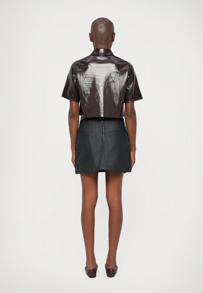 Rövid ujjú, fényes bordó ing, cropped fazonban, hegyes gallérral, fekete farmer mini szoknyával párosítva, hátsó cipzárral.