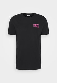 Camiseta de algodón negra con mangas cortas, con un diseño gráfico de texto rosa en la parte izquierda del pecho. Cuello redondo, corte estándar.