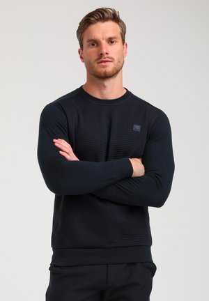 Sweatshirt bleu marine avec un motif de rayures diagonales texturé. Il présente un col rond et des manches longues. Logo discret sur la poitrine.