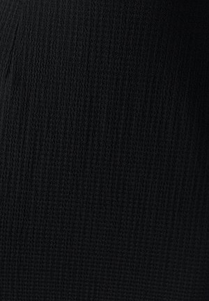 Čierny textúrovaný pletený materiál s vlnitým vzorom, ktorý má strednú hrúbku a mäkký povrch, vhodný na rôzne odevy.