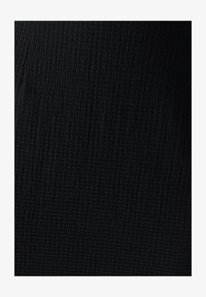 Tissu en tricot noir texturé avec un motif ondulé, présentant une épaisseur moyenne et une surface douce, adapté à divers vêtements.