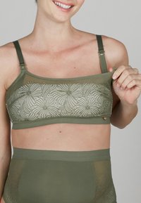 Olivengrünes Lingerie-Set mit einem strukturierten, halbtransparenten Bralette mit floralem Muster und verstellbaren Trägern, kombiniert mit passenden hochtaillierten Slips.