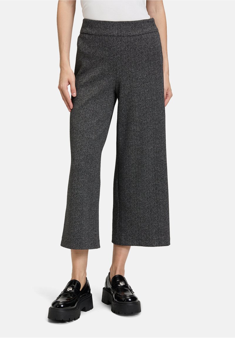 Pantalons larges gris en tissu texturé, avec une taille haute. Associés à des mocassins à plateforme noirs avec un accent métallique.