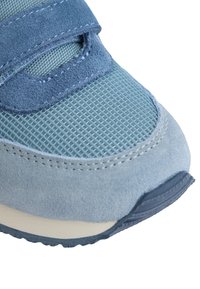 Zapatilla azul con parte superior de malla y acentos de ante, con una correa de velcro y suela texturizada para un mejor agarre. Diseño de punta curva.