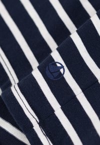 Marinblå och vit randig tyg med ribbad textur; har en liten logotyp i mörkblått. Ränderna är jämnt fördelade och horisontella.