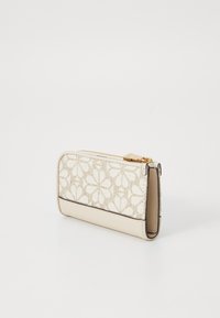 Beige plånbok med blomstertryck, guldfärgade detaljer, dragkedjestängning och en slät läderbotten. Kompakt rektangulär form.