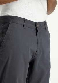 Donkergrijze broek van katoen, met een rechte voorkant, riemlussen en een knoopsluiting. Soepele textuur met gestikte details.