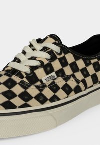 Нисък модел маратонки Vans с черно и кремаво каре, бели връзки и бяла гумена подметка с черна ивица.