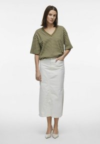 Camiseta oversized a rayas verde oliva con escote en V, combinada con una falda larga blanca con una abertura lateral y tacones de punta crema.
