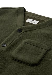 Maglione in feltro verde oliva con collo a scialle, tasca frontale e bottoni neri. Presenta una fodera interna liscia e un esterno morbido e strutturato.