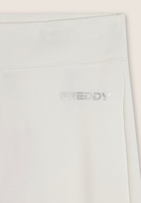 Pantaloni di cotone beige chiaro con una texture liscia e un logo riflettente argento "FREDDY" sulla cintura. Design semplice e colore sobrio.