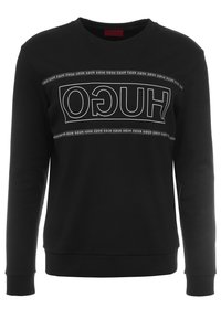 Schwarzer Pullover mit Rundhalsausschnitt, langen Ärmeln und einem auffälligen weißen "HUGO"-Logo auf der Brust in rechteckigem Design.
