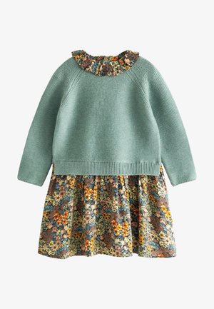 Haut en maille vert à manches longues avec jupe fleurie attachée et col volanté fleuri dans des tons orange, bleu, marron et crème.