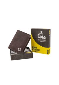 Cartera de cuero marrón con un adorno metálico circular, exhibida parcialmente abierta en una caja negra y amarilla etiquetada como "Accesorios genuinos".