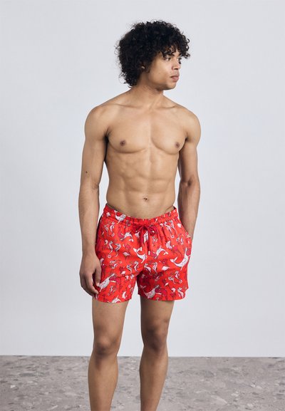 Raudoni maudymosi šortai su žaismingu baltos ir juodos jūros gyvūnų raštu, elastingu juosmeniu ir minkšta medžiagos tekstūra.