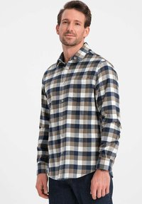 Camicia flanella da uomo in fantasia a quadri navy, grigia e beige. Presenta colletto, chiusura con bottoni, tasca sul petto e maniche lunghe. Tessuto morbido.
