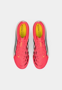 Φωτεινές ροζ ποδοσφαιρικές παπουτσές με υφή στην εξωτερική επιφάνεια, μαύρες ρίγες και γκρι λεπτομέρεια. Περιλαμβάνουν επενδεδυμένο εσωτερικό και σύστημα με κορδόνια.