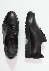 Černé kožené boty s texturovaným svrškem, šněrovací design, silná gumová podrážka a minimalistické detaily. Číslo stylu viditelné uvnitř.