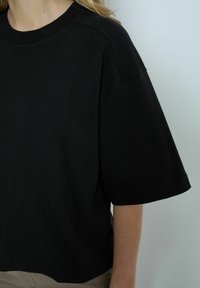 Black, short-sleeve t-shirt made of soft cotton, featuring a round neckline and relaxed fit with visible stitching details.