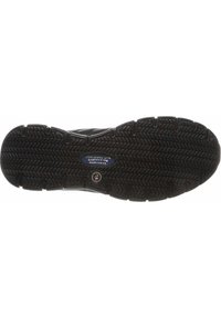 Semelle de sneaker en caoutchouc noir avec un motif de traction texturé. Arrière-plan d'un logo bleu et d'un emblème circulaire au centre.