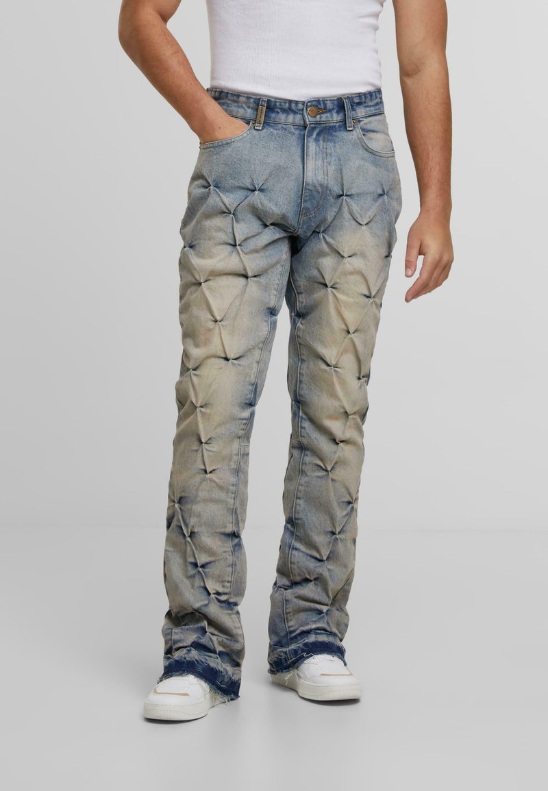 Wyblakłe dżinsy z teksturowaną, pikowaną powierzchnią i szerokimi nogawkami. Zawierają klasyczny pięciopocketowy krój oraz postrzępione końce.