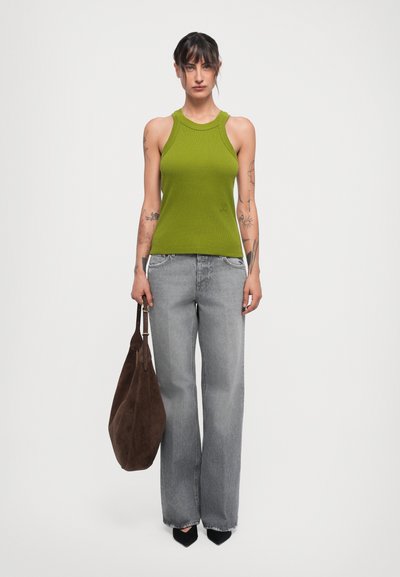 Canottiera verde a coste, jeans grigi a gamba larga, borsa in suede marrone morbida, décolleté nere a punta. Tatuaggi visibili sulle braccia.