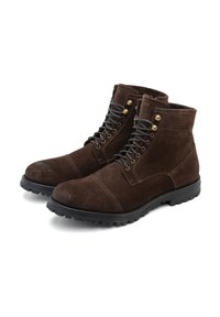 Stivaletti alla caviglia in suede marrone con suole in gomma nera, con occhielli dorati e lacci scuri, e un design della punta arrotondata.