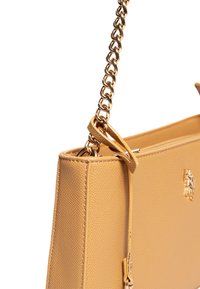 Borsa a tracolla in pelle color tan con superficie testurizzata. Presenta una tracolla in catena dorata e un emblema sul davanti. Forma rettangolare semplice.