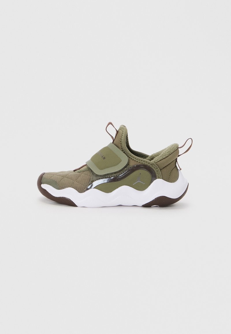 Baskets slip-on vert olive avec semelle blanche ondulée, tissu matelassé, sangle réglable, languettes de traction sur la languette et le talon, et logo discret sur le côté.