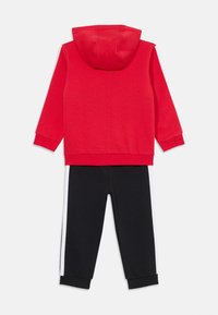 Red hoodie with a hood, paired with black sweatpants featuring white side stripes. Both items displayed flat against a white background.