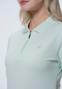 Helle mintgrüne Polo-Shirt mit Reißverschluss, kurzen Ärmeln und Logodetail. Glatte Textur und strukturiertes Kragen-Design.