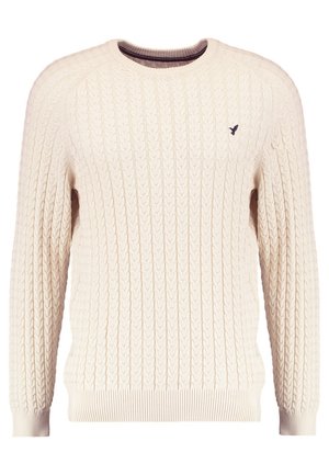 Cream cable-knit sweater with long sleeves and a crew neckline. Features ribbed cuffs and hem, with a small embroidered logo on the chest.