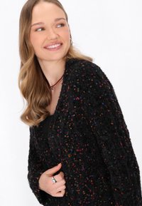 Cardigan nero in tessuto texturizzato e peloso, caratterizzato da macchie colorate. Il design è caratterizzato da una vestibilità ampia e un'apertura frontale, che ne esalta l'aspetto accogliente.