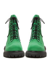 Botas de tobillo de cuero verde con cordones negros, suelas de goma y un acabado texturizado. Presentan un diseño elegante con detalles de costura pronunciados.