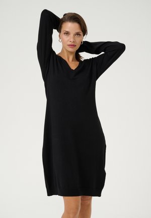 Robe noire en tricot avec des manches longues, un col en V et une coupe décontractée. Présente une texture côtelée et des poches sur les côtés. Design simple et polyvalent.