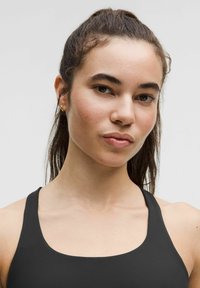 Top deportivo negro sin mangas con escote redondeado, ajuste contorneado y tirantes anchos. La tela parece suave y elástica. Diseño sencillo sin patrones.