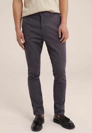 Chinos de mezcla de algodón grises con un ajuste slim, que presentan un cierre de botón, bolsillos laterales y una textura suave. Combinados con mocasines negros.