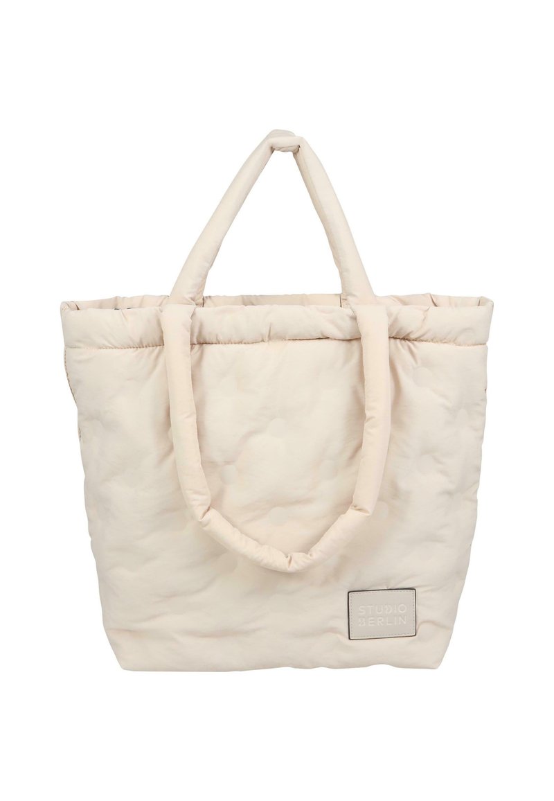 Sac à tote beige matelassé avec deux poignées en boucle, texture douce et une étiquette rectangulaire portant "STUDIO BERLIN" en gris.