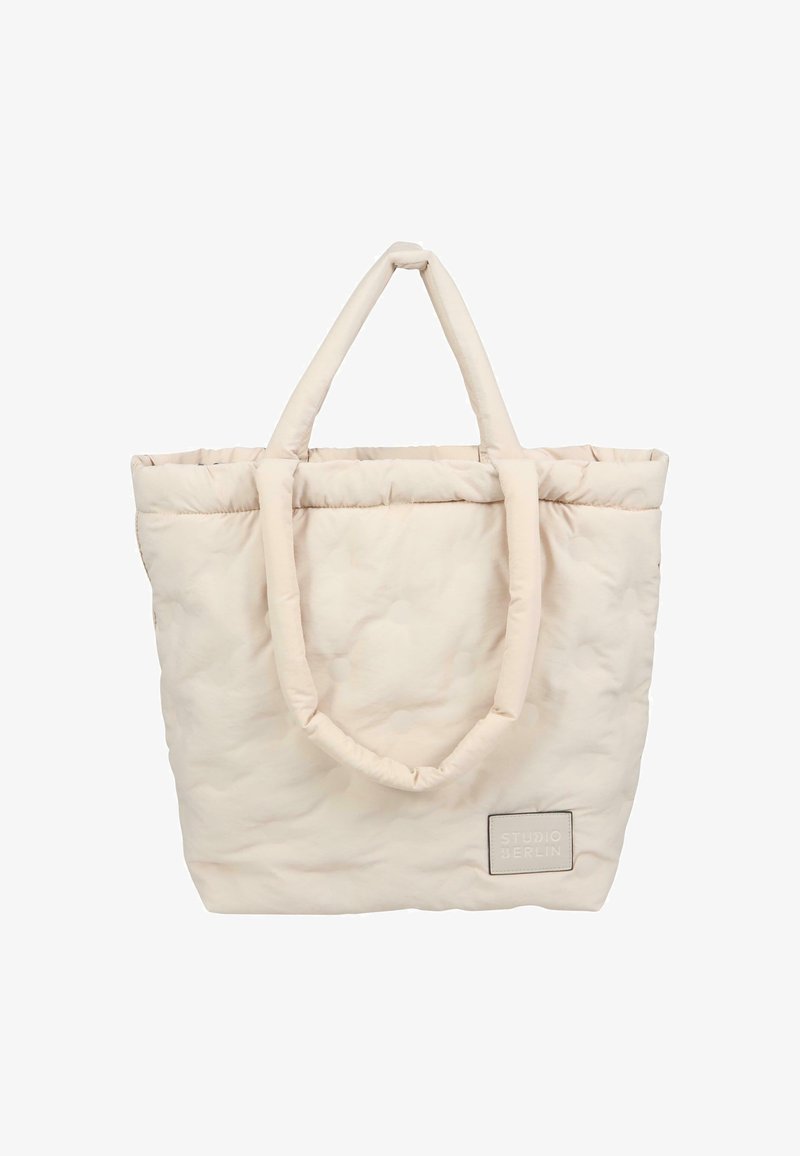 Beżowa torebka typu tote z pikowanym wzorem, z dwoma pętelkowymi uchwytami, miękka w dotyku, z prostokątną metką z napisem "STUDIO BERLIN" w szarym kolorze.