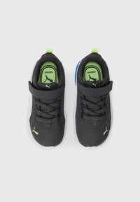 Une paire de baskets en mesh noires pour enfants avec des boucles vertes, des logos Puma vert citron et des semelles blanches, vues de dessus sur fond blanc.