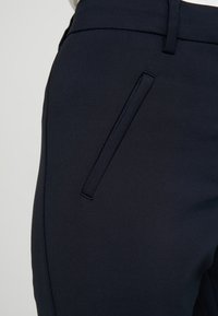 Navybyxor i ett slätt tyg med en sidofenol, ren design och minimala sömmar.