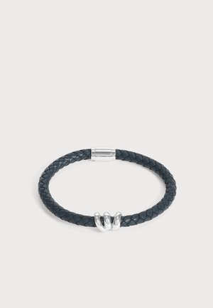 Bracelet en cuir noir tressé avec trois anneaux en argent poli et une fermeture magnétique en argent sur fond blanc.