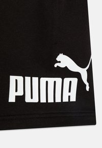 Μαύρο ύφασμα με λεία υφή διαθέτει μεγάλο, λευκό λογότυπο "PUMA" και τη σιλουέτα ενός πηδηχτού πούμα. Καθαρός σχεδιασμός με σαφή αντίθεση.