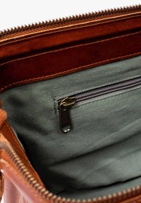 Brown leather bag interior with a green fabric lining, featuring a zippered pocket and a visible zipper along the edge.