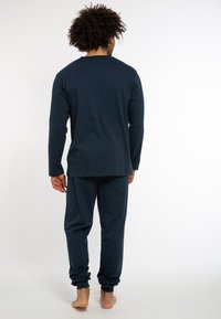 Navyblaues Langarmhemd und passende Hose aus weichem Stoff. Lässiger Schnitt mit schmal zulaufenden Säumen an der Hose. Einfaches, nahtloses Design.