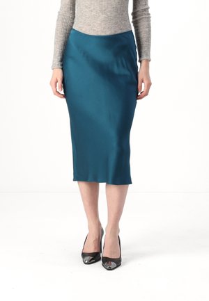 Tyrkis satin midi-skjørt med et glatt, kroppsnært design. Kombinert med svarte høye hæler med metalliske detaljer.