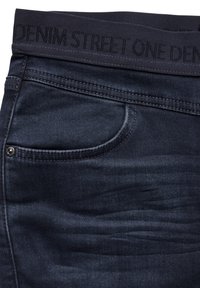 Mörkblå denimjeans med ett stretchigt midjeband som har texten "DENIM STREET ONE." Inkluderar en framficka och har en slät textur.
