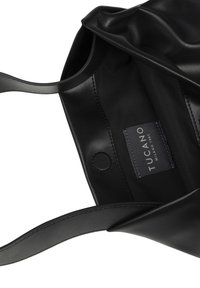 Sac fourre-tout en cuir noir avec une texture lisse, doté d'une étiquette grise cousue à l'intérieur. Comprend deux poignées robustes.