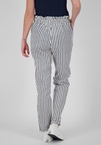 Pruhované kalhoty vyrobené z lehké tkaniny, s vertikálními námořnickými a bílými pruhy, volný střih, elastický pas a zúžené nohavice.